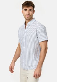 Camisa de botones de manga corta en blanco y rayas azul claro, hecha de un tejido ligero con una textura suave. Presenta un cuello de punta.