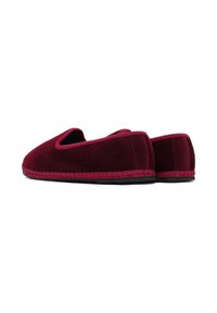 Une paire de chaussures plates sans lacets en velours rouge foncé avec un bord tissé et des semelles plates noires, présentée sous un angle latéral bas et de dos sur fond blanc.