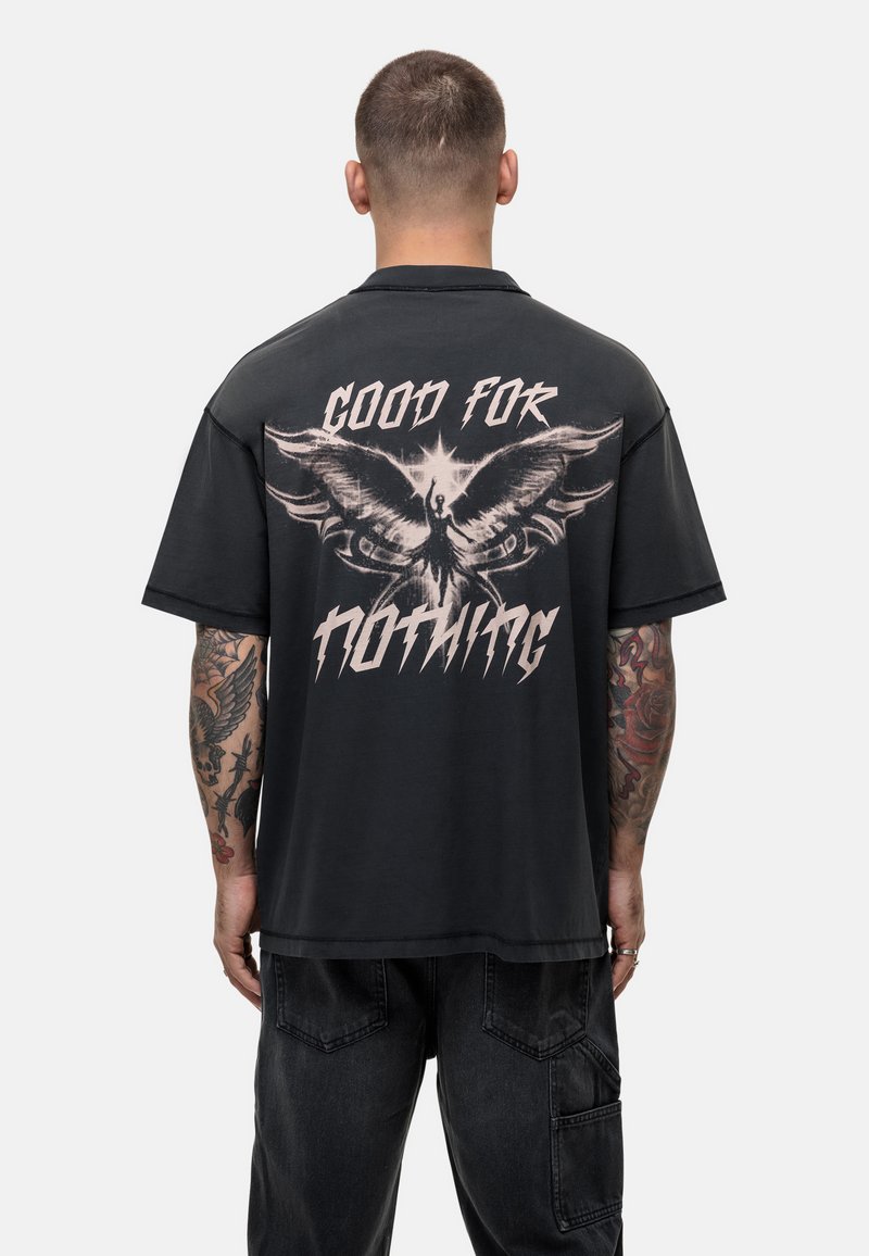Zwarte T-shirt met korte mouwen, voorzien van een groot ontwerp op de achterkant met een feniks en de tekst "GOOD FOR NOTHING" in vet, verweerd lettertype.
