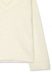 V-neck cream knit sweater with long sleeves, ribbed hem, and textured knit pattern. Fabric appears soft and lightweight.