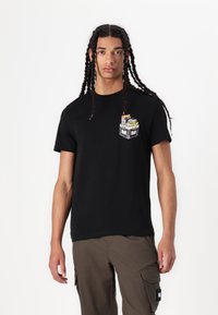 Black cotton t-shirt with a round neck, featuring a colorful graphic pocket design. Paired with olive green cargo pants.