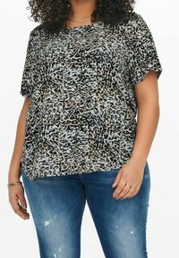 Top con stampa leopardata in azzurro chiaro, maniche corte, vestibilità ampia, texture trasparente, con tonalità di marrone e nero, abbinato a jeans blu scuro.