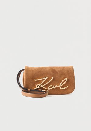Brun ruskind clutchtaske med guld "Karl" logo og justerbar tan læderstrop på hvid baggrund.
