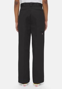 Zwarte wijde broek met een gladde textuur, voorzien van riemlussen, een ritszak en subtiele branding op de achterkant.