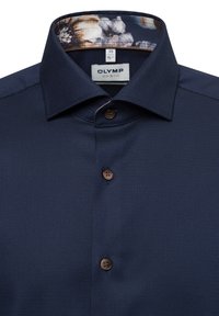 Dunkelblaues Hemd aus strukturiertem Stoff, mit kontrastierendem gemustertem Innenkragen und braunen Knöpfen. Etikett: OLYMP, Größe 39/15½.