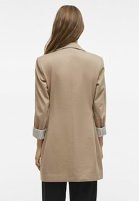 Giacca beige su misura dal design semplice, con maniche a righe arrotolate e una texture liscia. Taglio lungo, senza chiusure visibili.