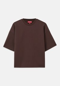 T-shirt oversize marron en coton, avec un col rond, des manches courtes et une étiquette au niveau du col avec un fond rouge.