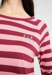 Gestreifter Langarm-Top aus bordeauxrotem und pinkem Baumwollstoff; hat einen runden Ausschnitt und den Text "ELB SAND" in Silber auf der Brust gedruckt.