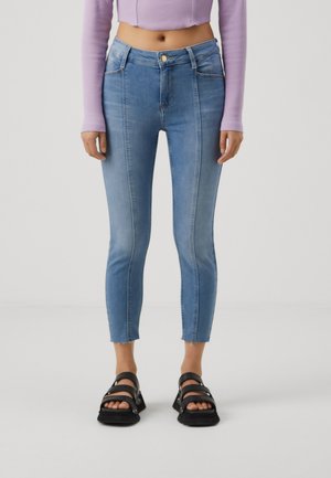 Light blue ankle-length jeans with a fitted design, featuring a high waist, frayed hem, and four pockets. Paired with black sandals.