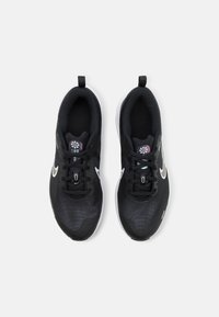 Baskets noires de sport avec un dessus texturé, accents blancs et un design à lacets. Comprend une languette à l'arrière pour un enfilement facile.