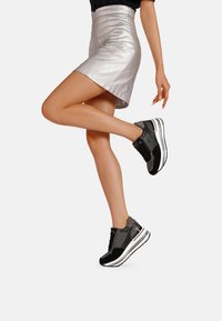 Le sneaker nere e grigie presentano un design in materiali misti con una finitura testurizzata, una suola intermedia bianca e una chiusura con lacci.