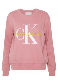 Sudadera rosa hecha de mezcla de algodón; cuenta con un cuello redondo, puños acanalados, un gran logo blanco "CK" y el texto amarillo "CALVIN KLEIN JEANS".