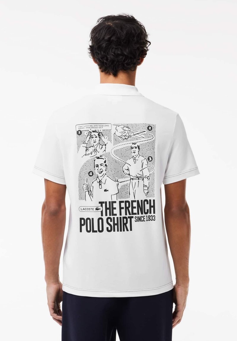 Polo-shirt blanc avec un graphique de style bande dessinée dans le dos, présentant des illustrations et du texte. Le tissu semble lisse avec un col classique.