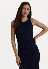 Sinen sininen sleeveless mekko, jossa on teksturoitu, ribattu kuvio ja istuva muoto. Pehmeä kangas, jossa on korkeampi kaula-aukko ja hienovarainen kiilto.