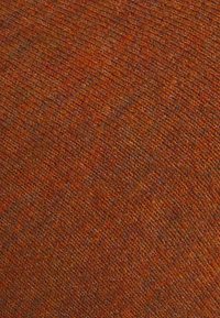 Texturerad tyg i rika orange nyanser, med ett vävt mönster som visar en blandning av varma färger med en mjuk finish.