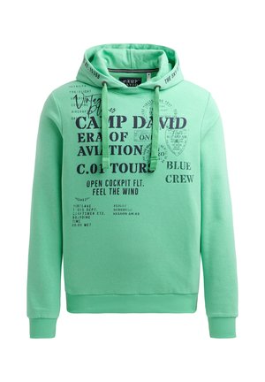 Grüne Kapuzenjacke aus weichem Material, ausgestattet mit einer Kapuze mit Kordelzug und verschiedenen schwarzen aufgedruckten Texten und Grafiken auf der Vorderseite.