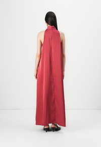 Lång röd satinklänning med halterneck och flödande design. Baksidan är slät och tyget har en subtil lyster.