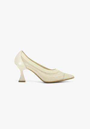 Chaussure à talon haut de couleur crème avec un bout pointu, un dessus en maille, et un design de talon triangulaire unique. Texture lisse avec des accents minimaux.