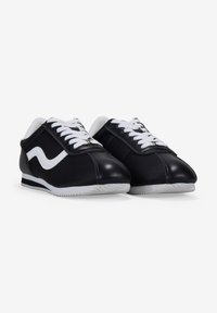 Black and white athletic shoes with a synthetic upper, lace-up closure, white accents, and textured rubber sole.