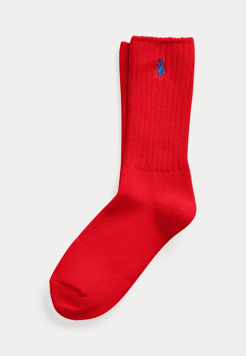 Κόκκινες ριγέ κάλτσες με λεία υφή, διακοσμημένες με ένα μικρό μπλε λογότυπο κοντά στην κορυφή. Σχέδιο μέχρι τον αστράγαλο.