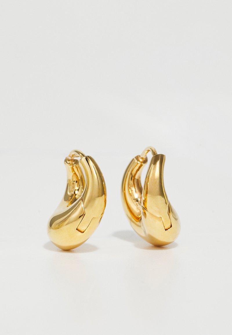 Goldene Creolen mit einer glatten, geschwungenen Form und polierter Oberfläche. Mit einem Verschlussmechanismus und leichten Einkerbungen für Details.