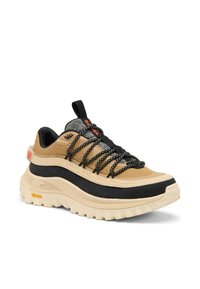 Baskets beiges et noires pour l'extérieur avec une semelle épaisse, des lacets noirs à motifs, une languette de tirage et une étiquette Gore-Tex sur le côté.