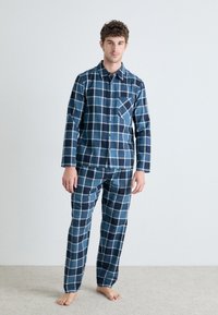 Pyjama à carreaux bleus comprenant un haut à boutons avec une poche et un pantalon assorti, fabriqué à partir d'un tissu doux avec une coupe décontractée.