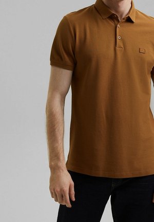 Polo shirt marron en tissu texturé, avec une patte de boutonnage à deux boutons et un petit logo sur la poitrine gauche. Manches courtes, design ajusté.