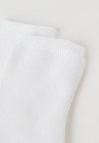 Hvide bomuldsstrømper med en glat overflade og elastisk top. Simpelt design uden mønstre eller detaljer, der fokuserer på funktionalitet.