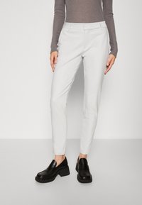 Ljusgrå, skräddarsydda byxor med smal passform och resårmidja. Kombinerat med svarta loafers med klossklack. Slät tygtextur.