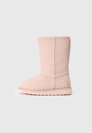 Botte d'hiver rose clair mi-mollet en matériau doux, semelle plate avec dessins, couture visible et logo brodé subtil près du talon.