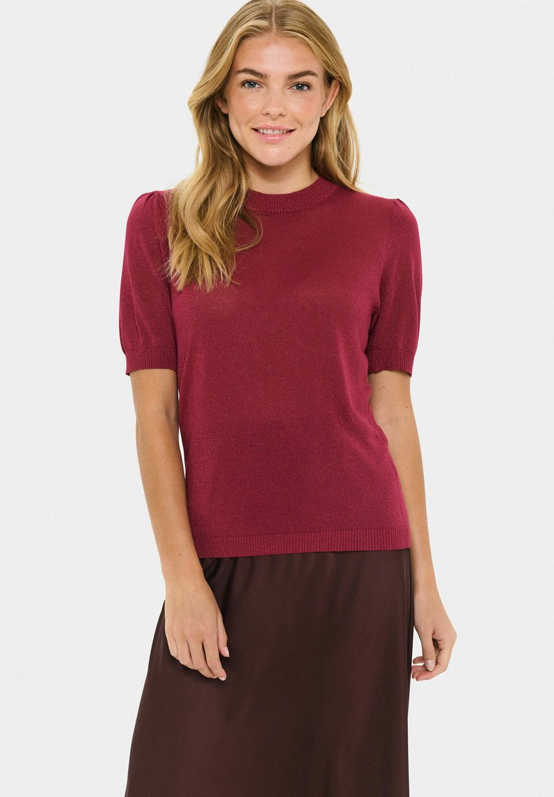 Burgundy short-sleeved knit top with a round neckline, ribbed cuffs, and hem. Smooth texture with slight shimmer, paired with a brown skirt.