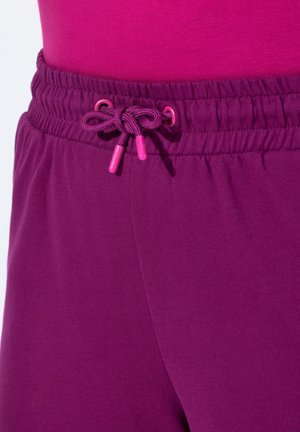 Fialové joggingové kalhoty s texturovaným pasem, se šňůrkou s růžovými špičkami. Hladká tkanina, těsně padnoucí silueta.