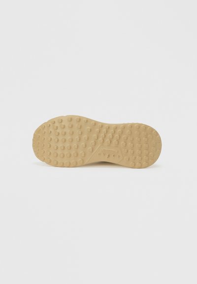 Σόλα παπουτσιού σε ανοιχτό μπεζ καουτσούκ, με υφή και ομοιόμορφα κατανεμημένα στρογγυλά αντιολισθητικά, καθώς και λογότυπο κοντά στο κέντρο.