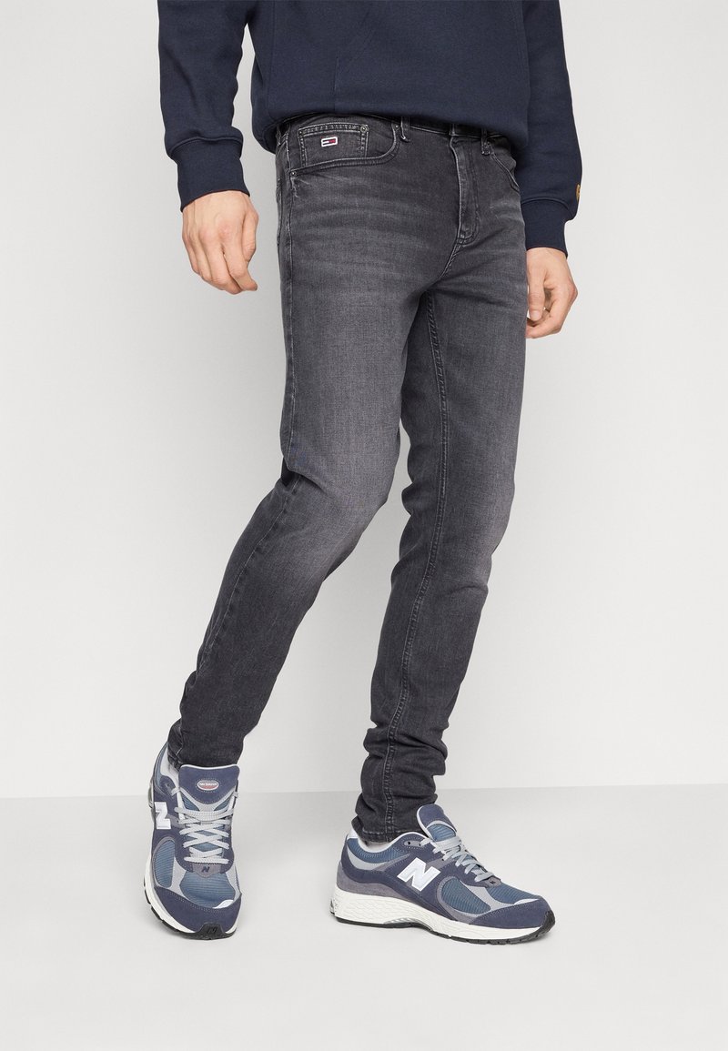 Smal passform grå jeans med en subtilt blekt design, fem fickor och en märkeslapp på midjan. Bärs med marinblå sportskor.