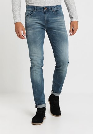 Blauwe denim jeans met een vervaagde afwerking, skinny fit, vijf zakken en een knoopsluiting. Gemaakt met zwarte suède enkellaarsjes.