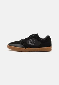 Pantofi de skateboard negri, fabricați din velur și plasă, cu o talpă din cauciuc, vârf rotund și un logo gri pe lateral. Șireturile plate completează designul.