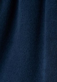 Tissu bleu foncé avec une surface tricotée douce et texturée, montrant de légers plis et ombres.