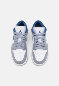 Paire de baskets Air Jordan blanches et grises avec logos Jumpman bleus et lacets gris, vues de dessus sur fond blanc.
