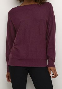 Lila, löst sittande tröja med breda axlar och ribbade ärmmuddar. Tillverkad av mjukt tyg, har en slät textur och en minimalistisk design.