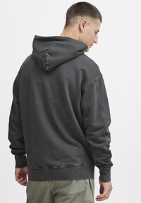Dunkelgrauer Hoodie mit strukturierter Oberfläche. Verfügt über eine Kapuze mit Kordelzug, gerippte Bündchen und Saum. Sichtbare Nähte setzen einen kontrastierenden Akzent.
