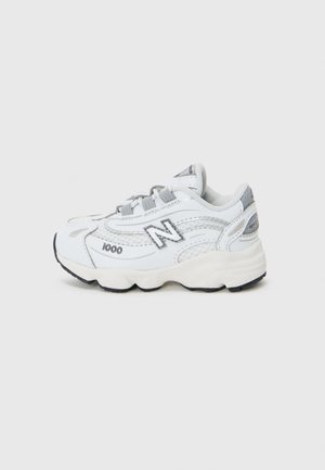 Des baskets New Balance blanches présentent une tige en mesh et en synthétique, une semelle rembourrée, des accents gris et un logo "N" bien en vue sur le côté.