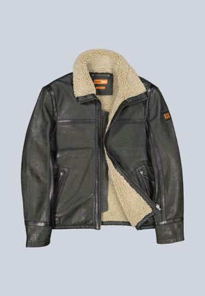 Schwarze Lederjacke mit cremefarbenem Schafsfellfutter, Reißverschluss vorne und zwei Fronttaschen. Auffälliges orangefarbenes Markenetikett am linken Ärmel.