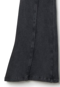 Zwarte denim uitlopende broek met een gladde textuur, voorzien van een nette zoom en zichtbare stiksels langs de zijkant.