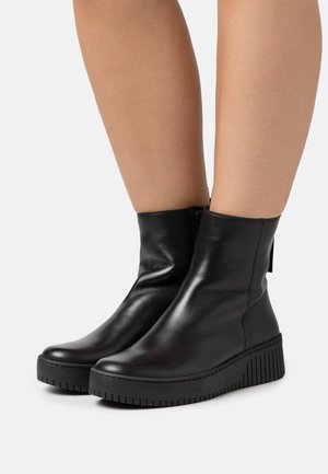 Black leather ankle boots with a rounded toe, a textured surface, and a thick, striped sole. Features a side zipper for closure.