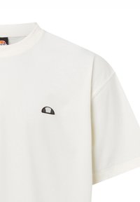 Camiseta de algodón blanca con cuello redondo y mangas cortas. Presenta un pequeño logotipo en blanco y negro en la parte izquierda del pecho. Textura suave.