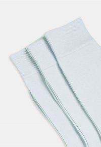 Jasnoniebieskie, prążkowane skarpetki bawełniane o gładkiej fakturze, z wzmocnionymi mankietami i subtelnymi zielonymi akcentami. Wyeksponowane trzy pary.