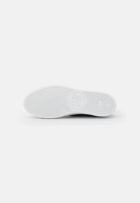 White rubber shoe sole with textured grip pattern, featuring a circular logo in the center. Flat design with rounded edges.