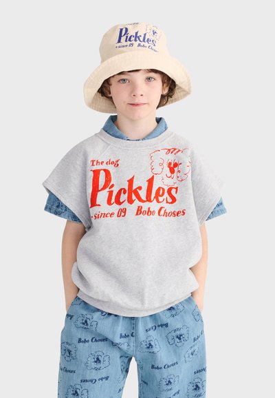 Enfant portant un chapeau seau beige, un t-shirt gris avec le texte rouge "Pickles" et un motif de chien, un short bleu à motifs avec des illustrations de chiens assorties.