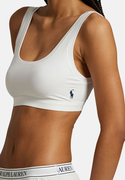 Γυναίκα που φοράει λευκό αθλητικό σουτιέν με ένα μικρό λογότυπο αλόγου και λευκά σορτς με ζωνάκι μέσης που φέρουν το κείμενο «Ralph Lauren».